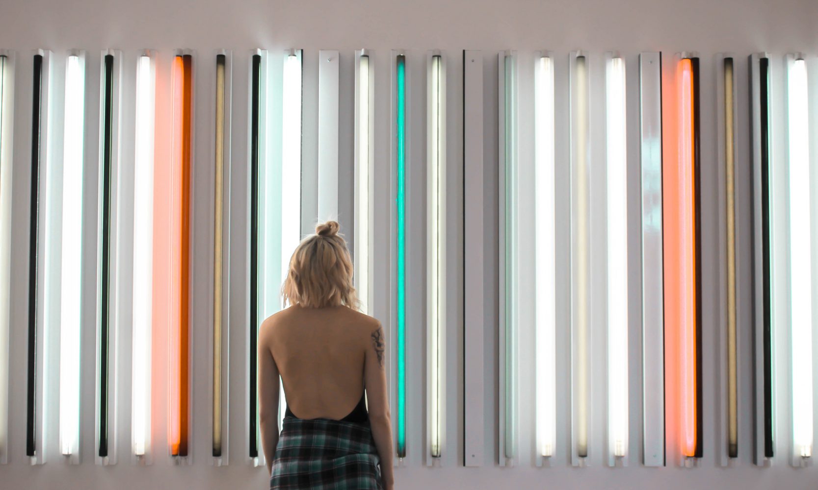 woman looking at neon light installation